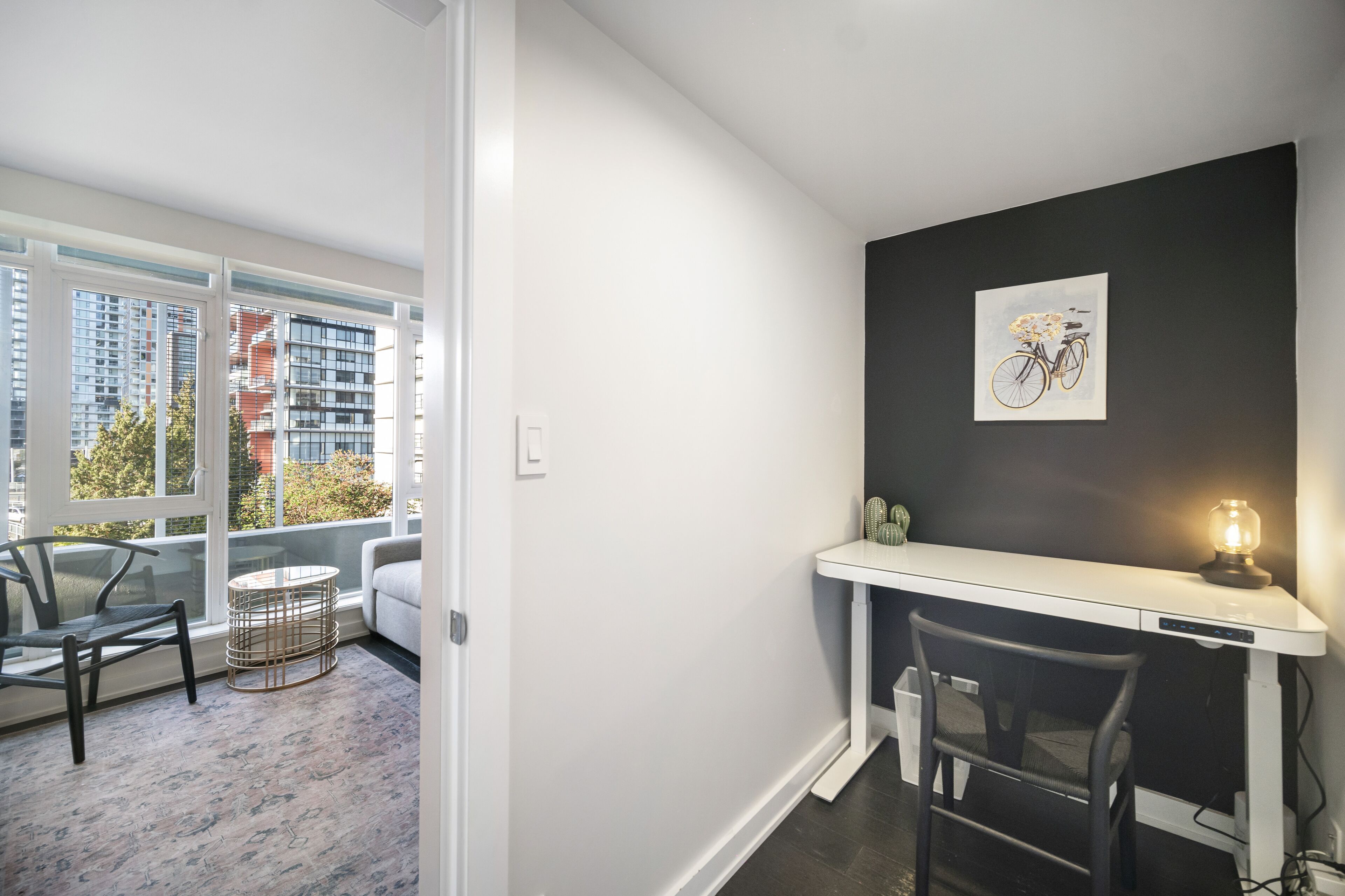 Une chambre moderne avec un bureau blanc, une chaise, une petite table et une lampe fixée au mur.
