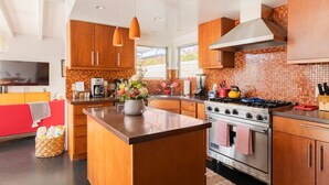 A modern kitchen with wooden cabinets, a central island, stainless steel appliances, and pendant lighting. - Unique 2 Master Suite Pool/ Spa Home, Relaxing Yard with Mountain Views (Palm Springs)