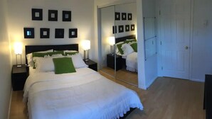 Ein ordentlich eingerichtetes Hotelzimmer mit einem großen Bett, Nachttischen, einem Spiegel und gerahmten Bildern an der Wand.
