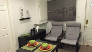 Ein modernes Wohnzimmer mit einem schwarzen Couchtisch, zwei grauen Sesseln und einem Stadtbild an der Wand.