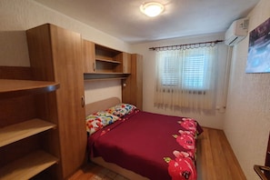 Une chambre à coucher avec un lit, une armoire en bois et une fenêtre avec des rideaux.