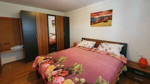 A bedroom with a bed, a nightstand, a wardrobe, and a painting on the wall. - Holiday flat with panoramic view and barbecue on the terrace (Gradinje)