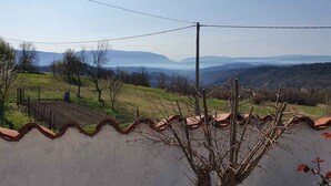 A rural landscape with a clear view of distant mountains, a fence, and a power line. - Holiday flat with panoramic view and barbecue on the terrace (Gradinje)