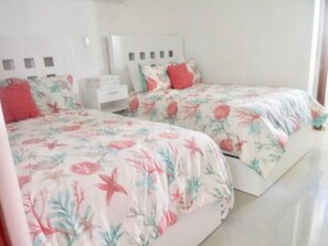 A bedroom with two beds, each with floral bedding and matching pillows. - Playacar Villa 10 pax ruins & beach (Playa del Carmen)