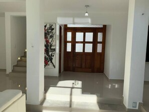 A spacious hallway with a wooden door, a staircase, and a modern light fixture. - Playacar Villa 10 pax ruins & beach (Playa del Carmen)