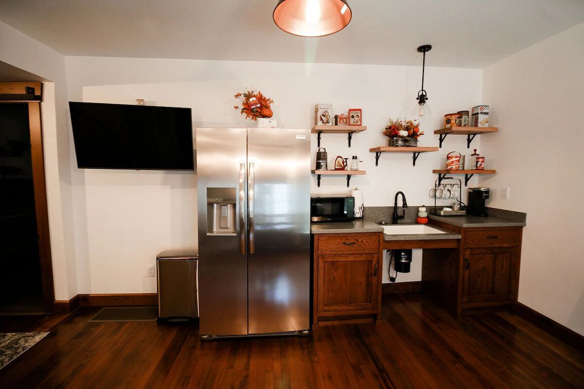A kitchen with a stainless steel refrigerator, wooden cabinets, a microwave, and a sink.