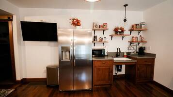 A kitchen with a stainless steel refrigerator, wooden cabinets, a microwave, and a sink.