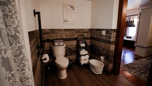 A bathroom with a toilet, a towel rack, a laundry basket, and a wooden wall.