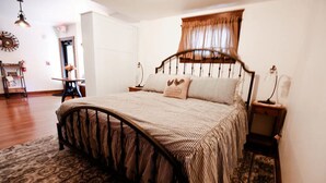 A bedroom with a bed, a nightstand, a lamp, a chair, a table, and a mirror.