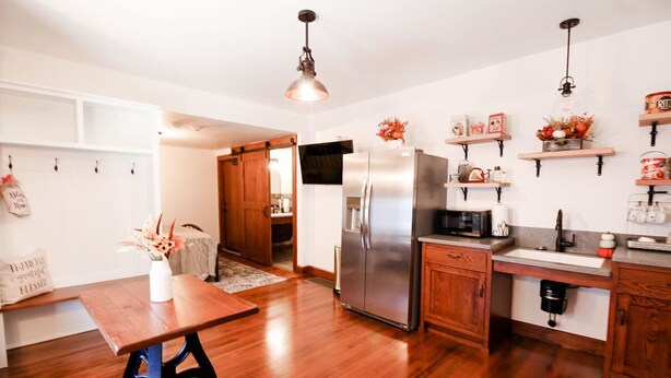 A modern kitchen with wooden flooring, stainless steel appliances, and a dining area with a wooden table.