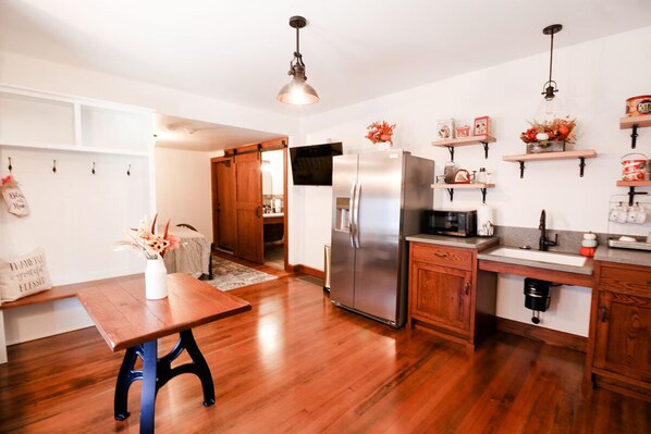 A modern kitchen with wooden flooring, stainless steel appliances, and a dining area with a wooden table.