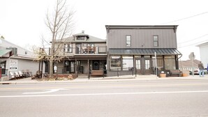 A two-story building with a balcony, a storefront with large windows, and a bench outside.