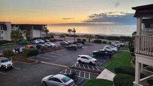 A parking lot with several cars and a view of the ocean at sunset. - stylish coastal condo with beautiful ocean views! (Myrtle Beach)