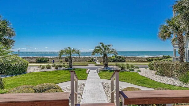 A pathway leading to a beach with palm trees and a clear view of the ocean. - stylish coastal condo with beautiful ocean views! (Myrtle Beach)
