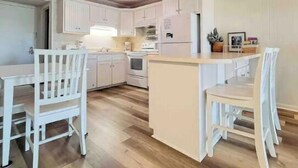 A kitchen with white cabinets, a wooden floor, and a ceiling fan. - stylish coastal condo with beautiful ocean views! (Myrtle Beach)