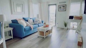 A bright living room with a blue sofa, white walls, and a view of the beach. - stylish coastal condo with beautiful ocean views! (Myrtle Beach)