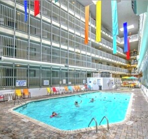 En indendørs swimmingpool med flere niveauer af balkoner, hvoraf nogle har gelændere og andre er åbne.