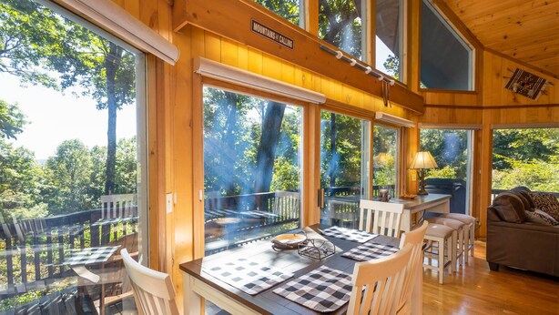 A wooden cabin with large windows, a dining area, and a cozy living space.