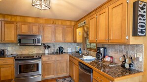 A kitchen with wooden cabinets, stainless steel appliances, and a stone backsplash.