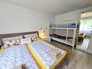 Et soveværelse med køjeseng, et natbord med lampe, et spejl og et vindue.