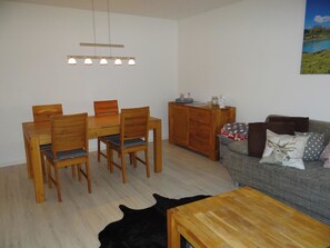 A living room with a wooden dining table and chairs, a sofa with patterned cushions, a wooden cabinet, and a painting on the wall. - Sunnmatt Süd Wohnung 432 Appartement/Fewo 4-Bettwohnung by Interhome (Engelberg)