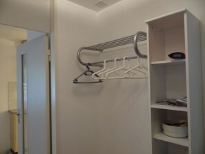 A bathroom with a towel rack, a shower, and a shelf with toiletries.