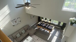 A spacious living area with a large sofa, a coffee table, and a pool table. There is a ceiling fan and a window providing natural light. - Vacation Home in Delmar (Delmar)