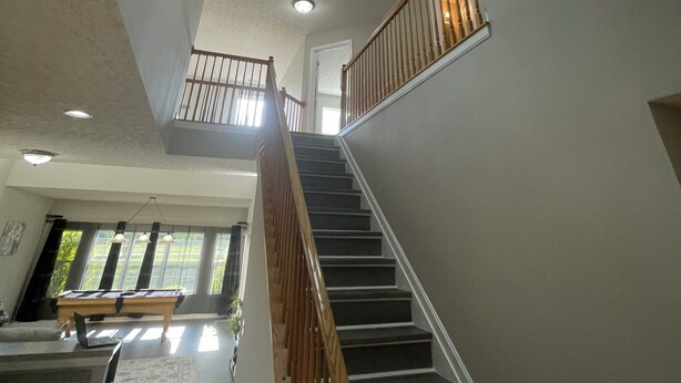 A spacious interior with a staircase leading to a balcony, modern lighting fixtures, and a view of the outdoors. - Vacation Home in Delmar (Delmar)