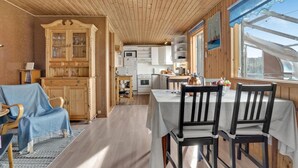 A cozy cabin interior with a dining area, wooden cabinets, and a kitchen.