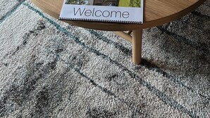 A round wooden coffee table with a hexagonal gold bowl containing golf balls and a welcome sign. - Modern 4BD in Katy TX (Katy)