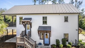 A two-story white building with a grey roof, a front porch, and a small attached garage. - Peaceful European Cottage with (Ocala)