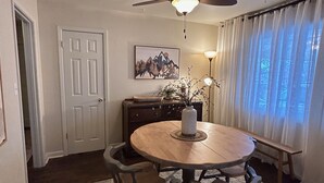 A dining area with a round table, four chairs, a ceiling fan, a vase, and a lamp. - Charming bungalow in the heart of Southwest Colorado (Cortez)
