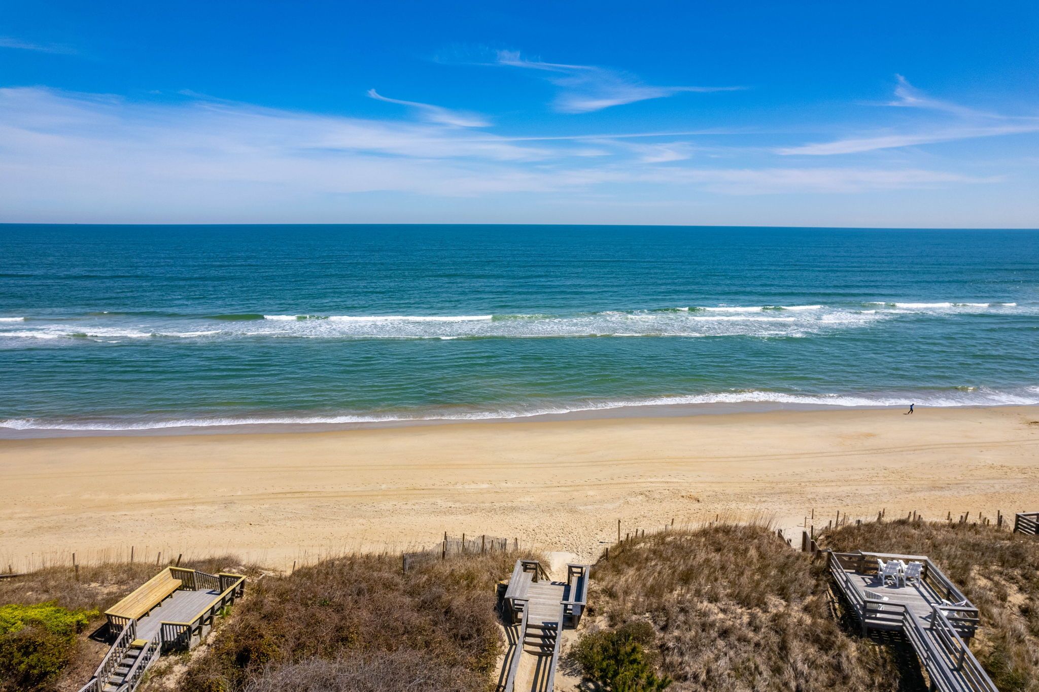 Une plage avec une promenade en bois qui mène à une étendue de sable.