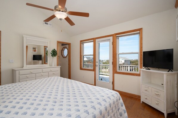 A bedroom with a bed, a ceiling fan, a TV, and a window with a view. - 123 Beach Therapy-Oceanside, private pool, hot tub, dog friendly, close to beach (Duck)