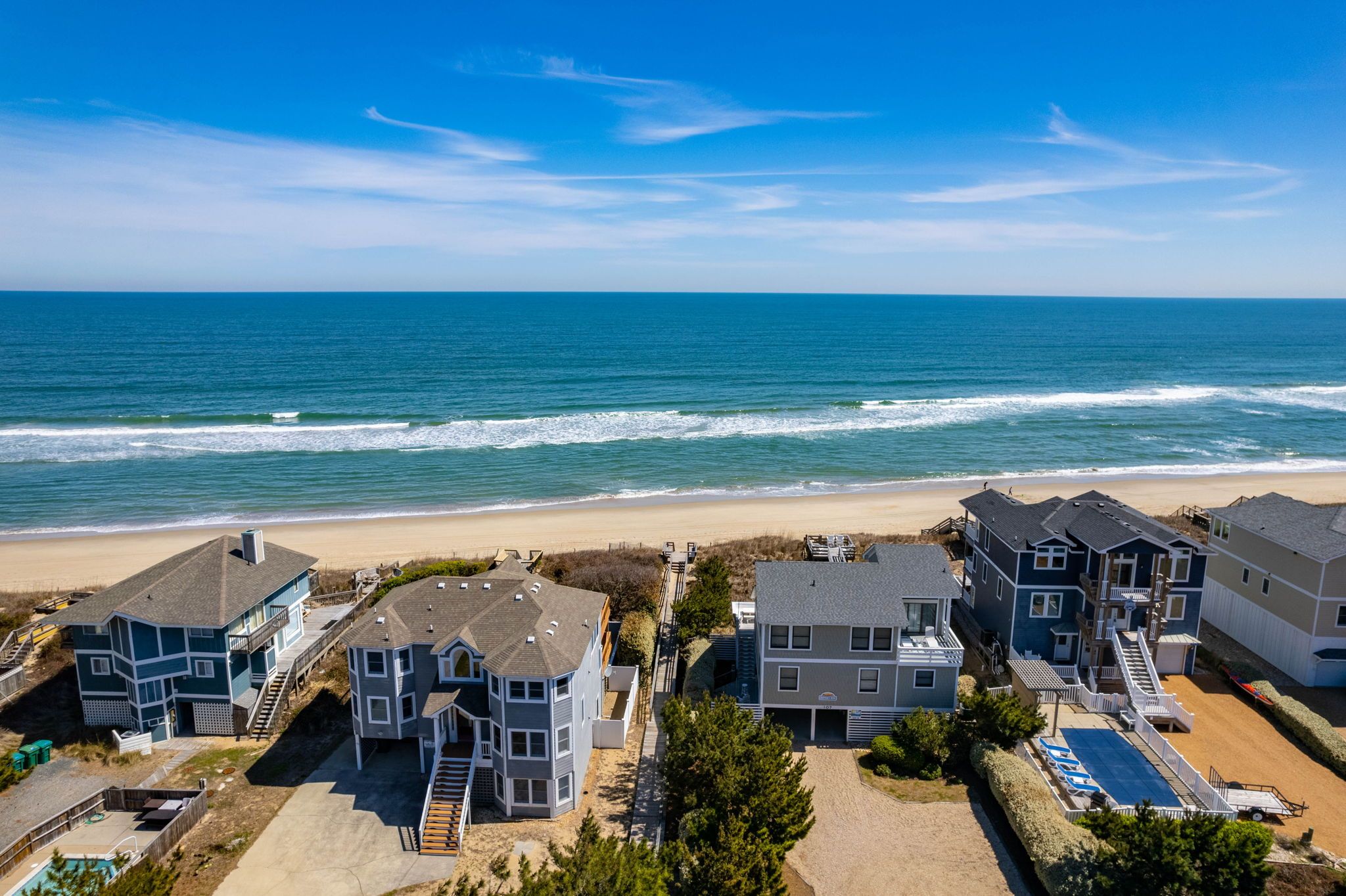 A coastal residential area with houses near the beach, featuring a clear view of the ocean and a sandy beach.