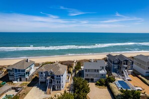 Un quartier résidentiel situé sur la côte, avec des maisons à proximité de la plage, offrant une vue dégagée sur l’océan et donnant accès à une plage de sable.