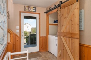 A cozy interior with a wooden door labeled "RELAX," a laundry area, and a view of a house outside. - 123 Beach Therapy-Oceanside, private pool, hot tub, dog friendly, close to beach (Duck)