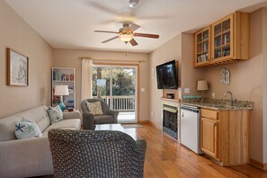 A spacious living area with a sofa, armchairs, a television, a fireplace, and a kitchen with wooden cabinets. - 123 Beach Therapy-Oceanside, private pool, hot tub, dog friendly, close to beach (Duck)