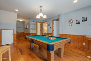 A pool table in a room with wooden floors and walls, a ceiling light fixture, and framed pictures on the wall. - 123 Beach Therapy-Oceanside, private pool, hot tub, dog friendly, close to beach (Duck)