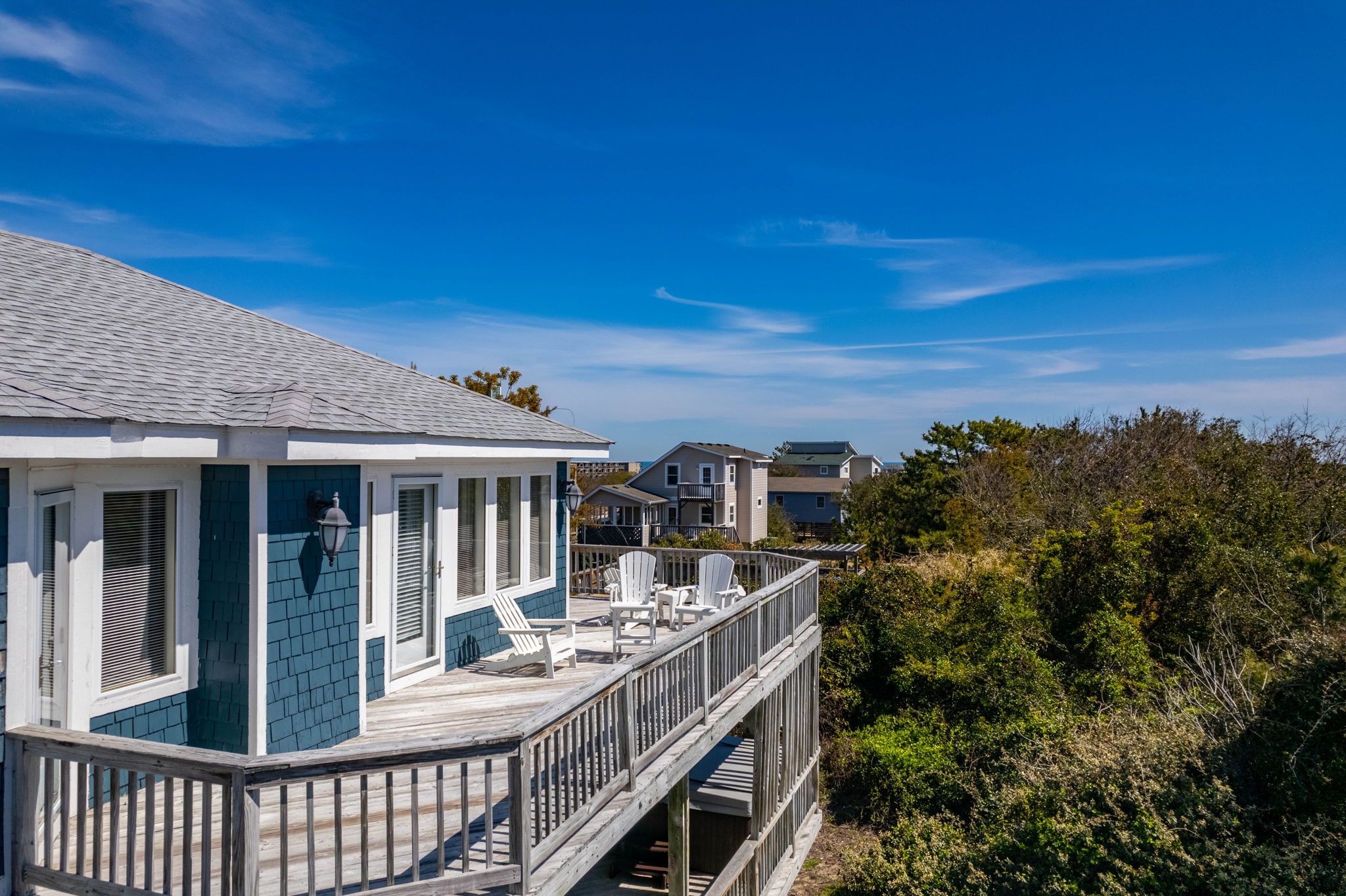 Una casa costera con terraza, varias ventanas y vista al mar.
