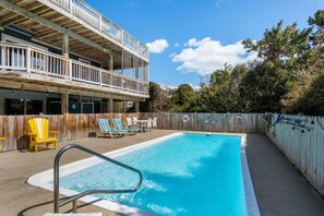Une piscine avec des chaises longues et une terrasse en bois.