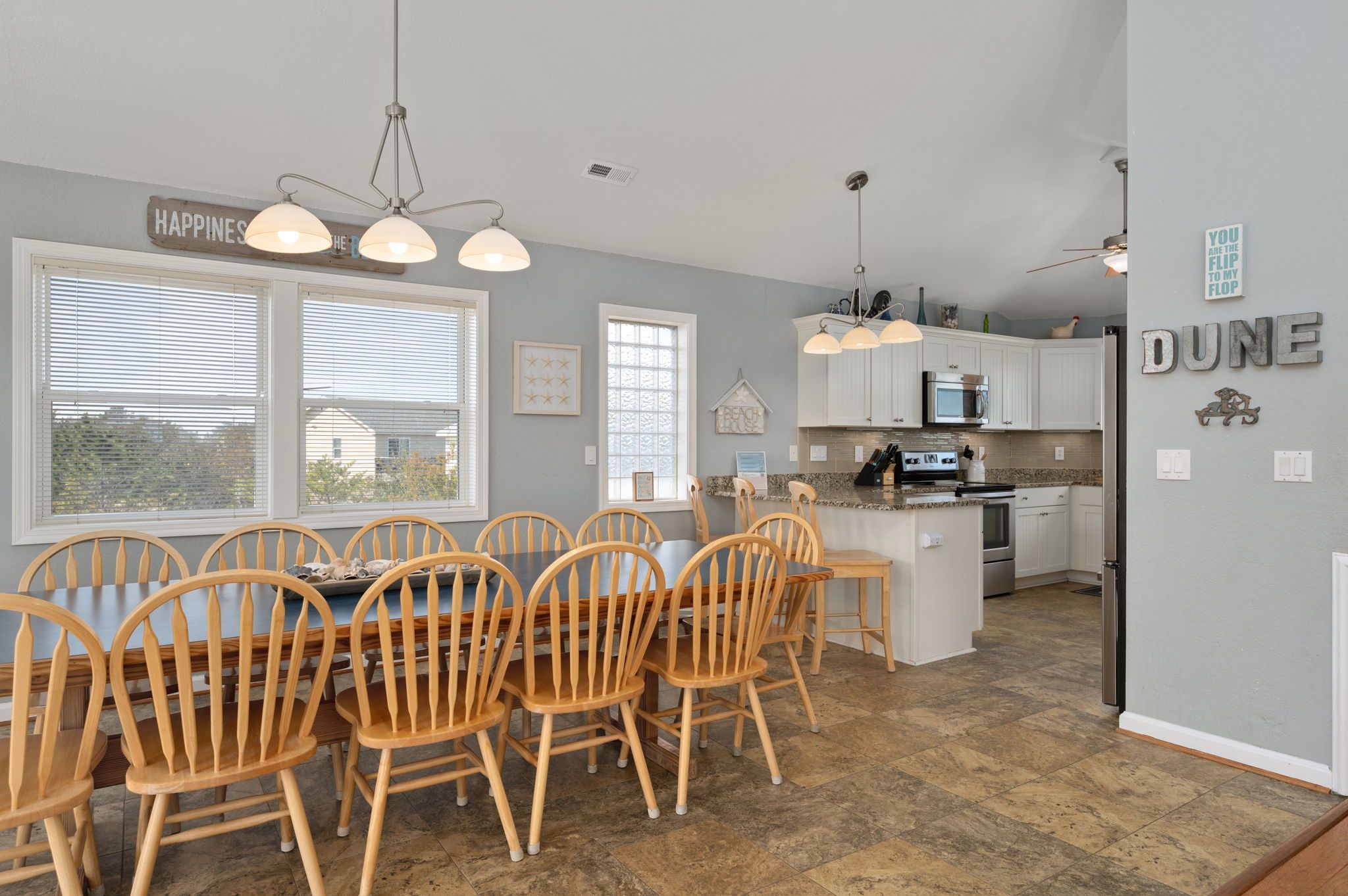 A spacious kitchen with white cabinets, a central island, and a dining area with wooden chairs.