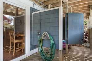 A covered outdoor area with a wooden deck, a green hose, and a blue utility box. - 123 Beach Therapy-Oceanside, private pool, hot tub, dog friendly, close to beach (Duck)