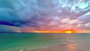 Ein Strand mit klarem türkisblauem Wasser und einem Sonnenuntergang.