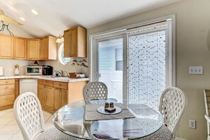 Enjoy meals in this kitchen with a dining table for two, microwave, and large window with blinds.