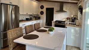 A modern kitchen with white cabinets, a stainless steel refrigerator, a built-in oven, and a large island with seating. -  HOT TUB and SAUNA at 'CHIC HIDEAWAY''  Paw Paw Lake Golf club across the street (Watervliet)