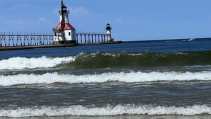 A lighthouse with a red roof and a white base, connected to a pier extending into the sea. -  HOT TUB and SAUNA at 'CHIC HIDEAWAY''  Paw Paw Lake Golf club across the street (Watervliet)