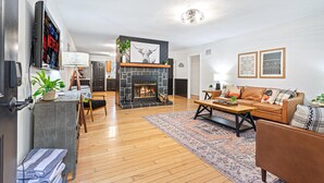Ein modernes Wohnzimmer mit Kamin, einer Sofagarnitur, einem Couchtisch und einem an der Wand montierten Fernseher.