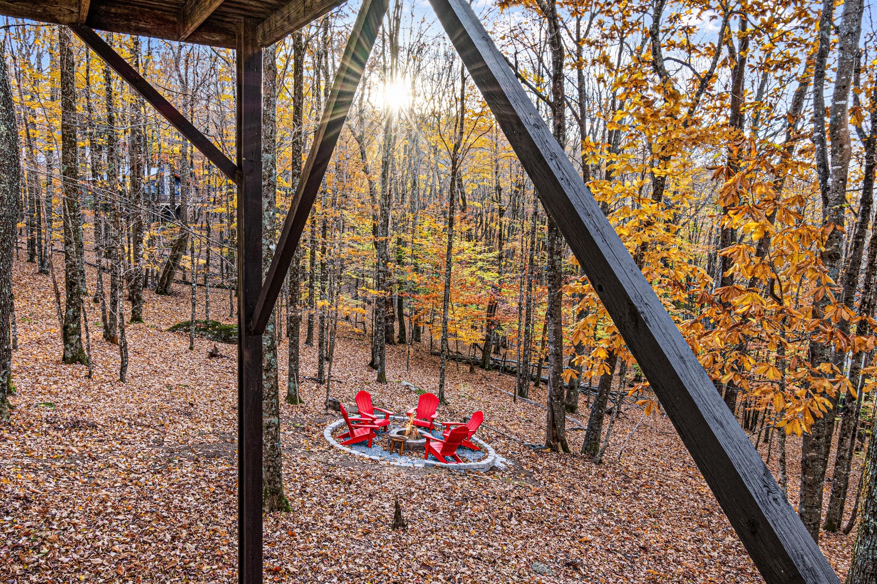 Une zone boisée avec une structure en bois comprenant un foyer et des chaises rouges.