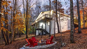 Eine Hütte mit einer Terrasse, einer Feuerstelle und Sitzgelegenheiten sowie einer Treppe, die zum oberen Bereich führt.